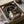 May include: Spirited Away movie poster in cardboard shipping box with protective wrapping, showing Chihiro character in green and white outfit standing in mystical stone tunnel with glowing red lanterns, surrounded by packing materials on white surface