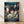 May include: Framed Spirited Away movie poster leaning against white wall on wooden floor. Features young girl with dark hair holding small object, surrounded by white spirits in traditional Japanese bathhouse setting with red lanterns. Colorful anime artwork in natural wood frame with soft shadows from window light.