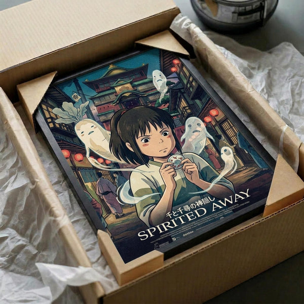 May include: Framed poster artwork featuring Chihiro from Spirited Away surrounded by white soot sprites in a magical bathhouse setting with traditional Japanese architecture, red lanterns, and intricate details. The poster sits in a cardboard shipping box with protective wrapping paper, photographed on a white surface next to a dark glass bowl.