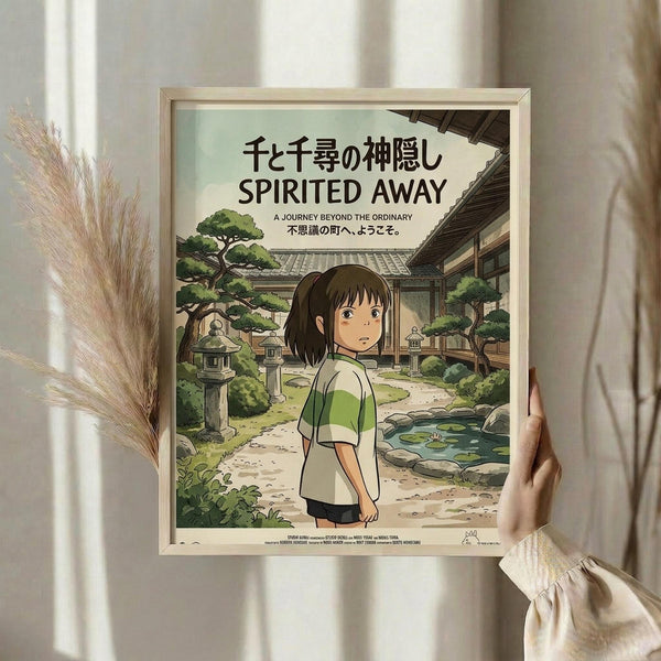 May include: Framed Studio Ghibli Spirited Away poster held by person in cream sweater against white curtained window. Artwork shows young girl with brown bob haircut in green and white striped shirt standing in traditional Japanese garden courtyard with stone lanterns, pond, and wooden buildings. Natural wood frame, soft window lighting, dried pampas grass visible to left.