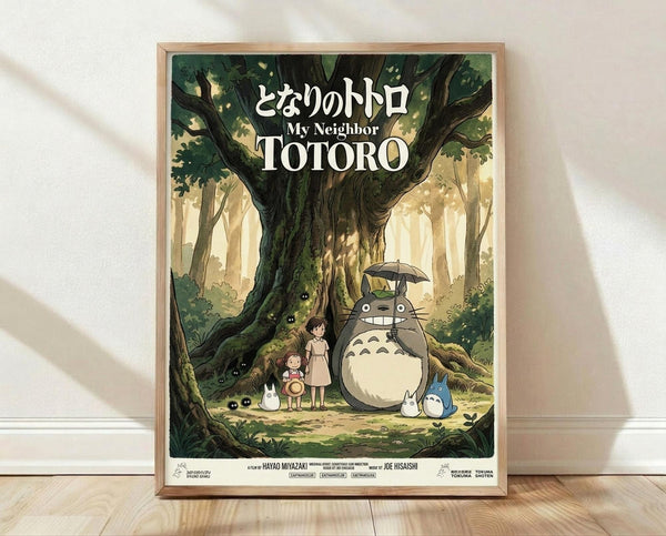 May include: Framed poster displaying Studio Ghibli's My Neighbor Totoro artwork in soft forest greens and warm golden light. Shows large gray Totoro character with umbrella standing beside two children under a massive tree trunk, with smaller white and blue totoro creatures nearby. Japanese and English text at top. Natural wood frame against white textured wall on light wooden floor with soft shadows.