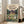 May include: Framed poster displaying animated scene with large gray forest creature, children, and house in background, leaning against white wall next to beige couch in bright living room with hardwood floors and large windows
