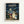 Framed poster featuring the iconic Studio Ghibli film My Neighbor Totoro in a light wood frame against a white wall. The artwork shows two young girls with umbrellas standing at a rainy bus stop next to the large gray Totoro character and smaller blue Totoro, all sheltering from heavy rain under a street lamp. Japanese text appears at the top with English translation below. The scene captures the magical, nostalgic animation style with muted blues and greens depicting the stormy evening atmosphe
