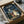 May include: Vintage-style My Neighbor Totoro poster in wooden frame, nestled in cardboard shipping box with protective tissue paper. The colorful artwork shows Totoro and smaller spirit creatures with children holding umbrellas in a rainy night scene with Japanese text at top. Frame appears medium-sized relative to the brown cardboard packaging materials surrounding it.