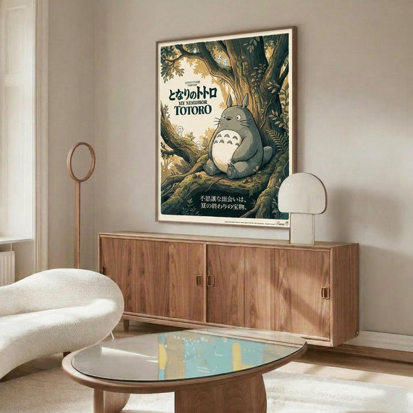 May include: My Neighbor Totoro vintage-style poster mounted on white wall above mid-century modern walnut credenza in minimalist living room. Poster shows gray Totoro character sitting in lush green forest with Japanese text. Room features cream upholstered swivel chair, oval glass coffee table, white table lamp, and wooden floor lamp. Warm natural lighting creates cozy atmosphere with beige walls and contemporary Scandinavian-inspired furniture.
