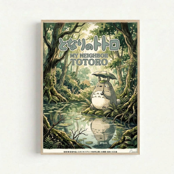 May include: Framed poster artwork showing the beloved gray forest spirit Totoro holding a small umbrella while standing in a lush, green woodland setting beside a tranquil pond. The character's reflection appears in the water below. Dense trees with moss-covered trunks and vibrant foliage surround the peaceful scene. Japanese and English text appears at the top. The print is displayed in a light wooden frame against a white wall, showcasing the detailed Studio Ghibli-inspired illustration in so