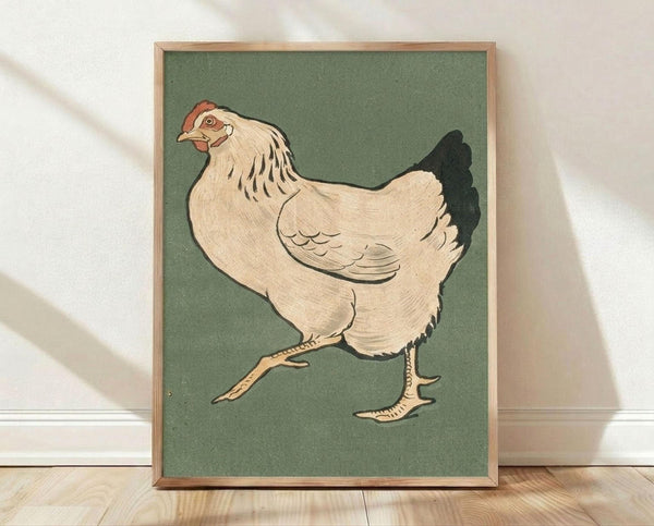 May include: Framed vintage Japanese woodblock print of a plump white hen with black tail feathers and red comb, illustrated in muted earth tones against sage green background. The artwork is displayed in a light wood frame, leaning against a white wall on wooden flooring with natural sunlight casting shadows across the scene.