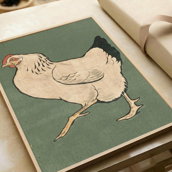 A vintage Japanese woodblock print of a plump white hen with black tail feathers and orange comb, walking on thin legs against a muted sage green background. The artwork shows fine line details and soft, natural coloring typical of early 20th century bird illustrations. The print is displayed on cream colored paper with neutral ribbon nearby, showing the artwork's actual size and framing presentation.