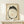 May include: Framed Japanese ink painting of a minimalist frog in black brushstrokes forming a circular shape with googly eyes and webbed feet, featuring a red square seal stamp, displayed on light wood shelf next to small white gift box with evergreen sprig against cream wall