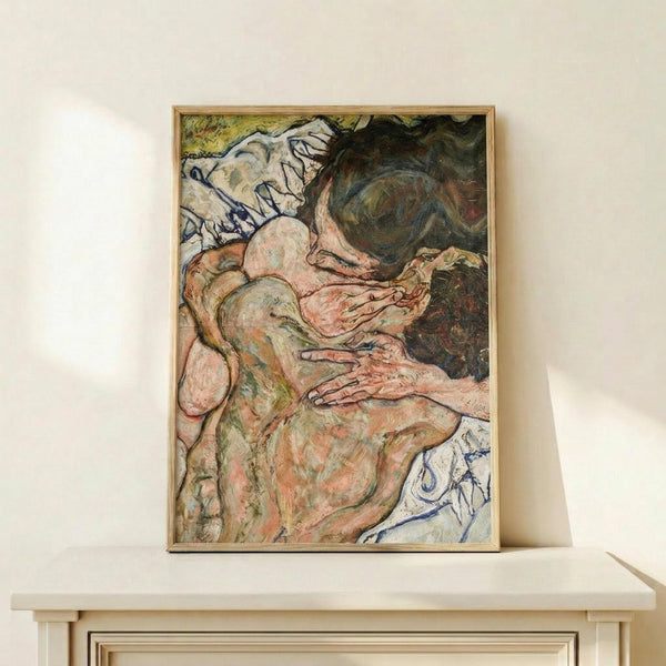May include: Framed reproduction of an expressionist painting showing two intertwined nude figures rendered in muted pink, green and earth tones with bold black outlines. The artwork is displayed in a thin wooden frame on a light wood floating shelf against a cream wall, with natural lighting creating soft shadows.