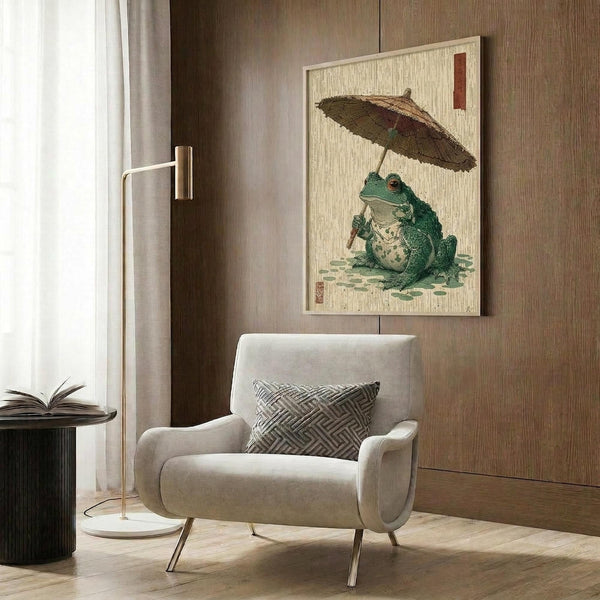 May include: Japanese-style woodblock print artwork showing a green frog holding a traditional bamboo umbrella, displayed in a light wooden frame against wood-paneled wall. Modern beige armchair with geometric patterned pillow sits below, alongside brass floor lamp and dark side table with open book. Cream curtains and warm wood tones throughout the contemporary living space.