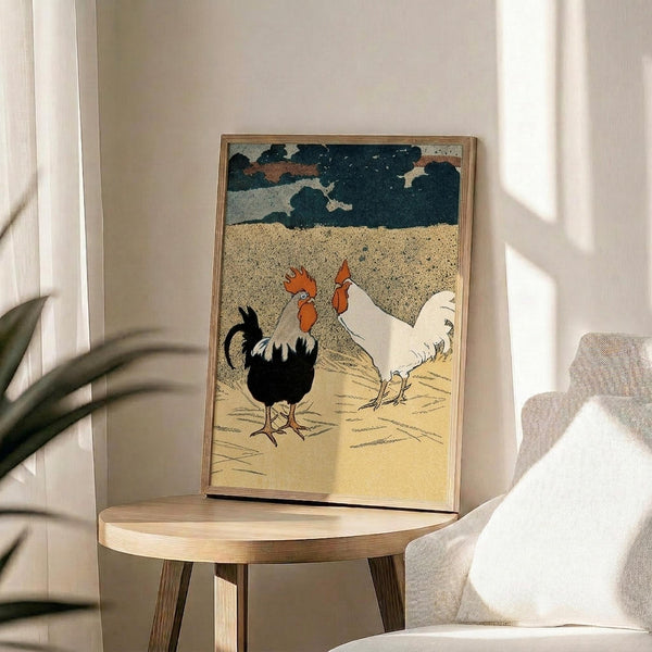 May include: Framed vintage-style print featuring two roosters - one black with white neck feathers, one white - standing on sandy ground beneath a stormy sky with dark blue-green clouds. The artwork has a textured, woodblock print appearance with muted colors. The thin wooden frame rests on a small round wooden side table next to a beige upholstered chair in a bright, minimally decorated room with white walls and natural sunlight streaming in.