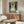 May include: Framed poster featuring a gray tabby cat wearing black headphones on teal vintage-style background with cream text and musical note graphics, displayed above walnut wood credenza in modern living room with white curved chair, glass coffee table, and neutral decor