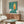 May include: Vintage-style poster with turquoise speckled background featuring yellow and orange flame design mounted above wooden sideboard. Modern living room setting with white curved chair, glass-top coffee table, and minimalist decor. Poster appears medium-sized in thin frame against neutral wall.