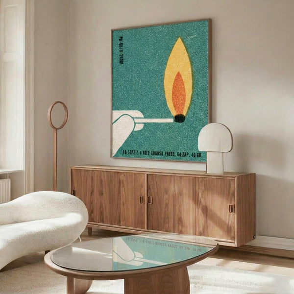 May include: Vintage-style poster with turquoise speckled background featuring yellow and orange flame design mounted above wooden sideboard. Modern living room setting with white curved chair, glass-top coffee table, and minimalist decor. Poster appears medium-sized in thin frame against neutral wall.