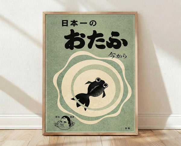 May include: A framed vintage-style poster with sage green background featuring a black goldfish swimming in concentric cream and green circles. Japanese text appears at the top in bold black characters, with smaller text reading "今から" (ima kara). A small illustrated face appears in the bottom left corner. The wooden-framed artwork leans against a white wall on light wooden flooring, with soft natural lighting creating gentle shadows.