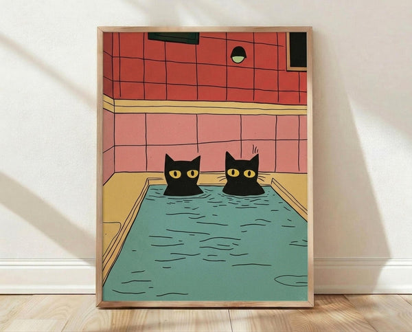 May include: Framed poster print leaning against white wall on light wood floor. Artwork shows two black cats with bright yellow eyes soaking in turquoise bath water inside wooden bathtub. Background features coral and salmon pink tiled bathroom walls with black geometric elements and circular window detail. Illustration has clean cartoon style with bold colors and simple lines.