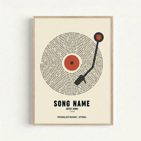 Framed poster print featuring a vinyl record design made from spiraling text lyrics in black ink, with orange-red center label and black tonearm. Below reads "SONG NAME", "ARTIST NAME", "YEAR", and "PERSONALIZED MESSAGE - OPTIONAL" in black text on cream background. Light wood frame against white wall.