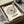 May include: Framed vinyl record-style poster with song lyrics arranged in concentric circles around red center label, black tonearm graphic, customizable song and artist text at bottom. Black frame in cardboard box with tissue paper wrapping, wooden surface background.