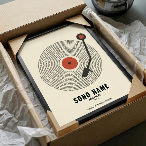 May include: Framed vinyl record-style poster with song lyrics arranged in concentric circles around red center label, black tonearm graphic, customizable song and artist text at bottom. Black frame in cardboard box with tissue paper wrapping, wooden surface background.