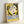 Framed vintage exhibition poster featuring a stylized face illustration in black, cream and yellow. The minimalist design shows a woman's profile with closed eyes and flowing hair in Matisse's signature cut-out style. Blue text reads "HENRI MATISSE MAISON DE LA PENSEE FRANCAISE CHAPELLE PEINTURES DESSINS SCULPTURES" against a bright yellow background. The poster is displayed in a light wood frame leaning against a white wall.