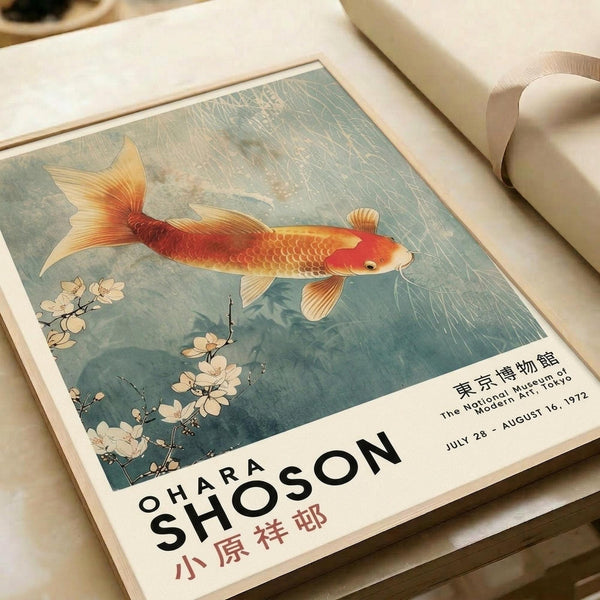 May include: Vintage exhibition poster featuring a golden-orange koi fish swimming among delicate white cherry blossoms against a muted blue-green background. The artwork shows Japanese woodblock print styling with fine linear details. Text at bottom reads "OHARA SHOSON" with Japanese characters and museum exhibition dates from 1972. Poster displayed on cream bedding with neutral ribbon visible.