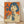 May include: Framed vintage-style poster with orange and cream color scheme featuring a woman with dark bob haircut holding a glass Coca-Cola bottle, Japanese text characters on left side, displayed against white wall on light wooden floor with natural lighting creating soft shadows