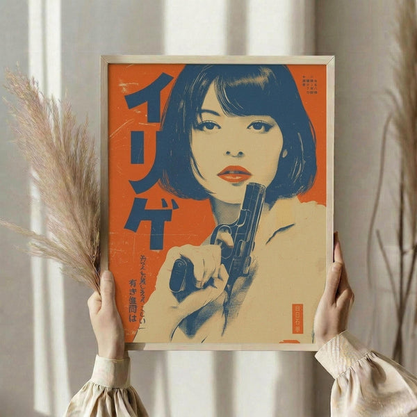 May include: Person in cream dress holding framed vintage-style poster featuring woman with dark bob haircut holding gun, set against bright orange background with Japanese text. Person also holds dried pampas grass stems. Soft natural lighting near white curtained window creates warm, aesthetic styling scene.