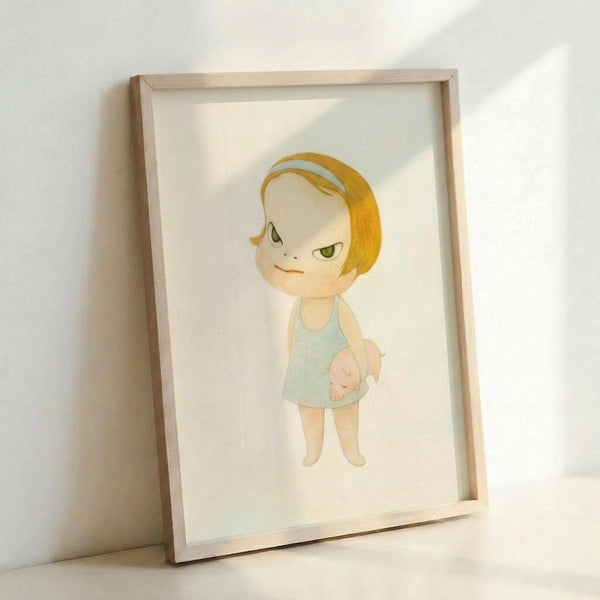 May include: Framed art print leaning against white wall showing cartoon-style illustration of blonde child character with green eyes wearing light blue tank top, holding small pink pig toy. Artwork has soft watercolor appearance on cream background within natural wood frame.