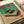 May include: Vintage-style poster featuring retro turntable with red vinyl record on green and cream background with Japanese text, displayed on white couch with paper tube nearby. Bold red katakana characters across top, detailed technical illustration style with weathered textures and authentic 1970s aesthetic.