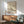 May include: Framed vintage Japanese art poster featuring white bird perched on flowering cherry blossom branches against cream background, displayed above mid-century modern wooden credenza with table lamp, next to sage green upholstered armchair with wooden arms in sunlit room with white walls