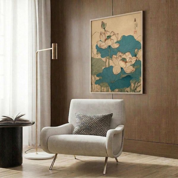 May include: Framed botanical print featuring white lotus flowers with large teal-blue leaves in traditional Japanese art style, displayed on wood-paneled wall above cream upholstered armchair with geometric patterned pillow, brass floor lamp and dark side table with open book nearby