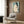 May include: Japanese woodblock print artwork displayed in modern living room setting with beige armchair, brass floor lamp, and wood paneling. The vintage poster shows a seated nude woman with black hair against turquoise background in traditional ukiyo-e style, framed in light wood frame.