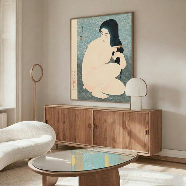 May include: Japanese woodblock print showing woman with long black hair combing her hair, seated nude against turquoise background, displayed in thin gold frame above mid-century walnut credenza. Modern living room setting with white curved chair, brass floor mirror, white table lamp, and glass coffee table on area rug.