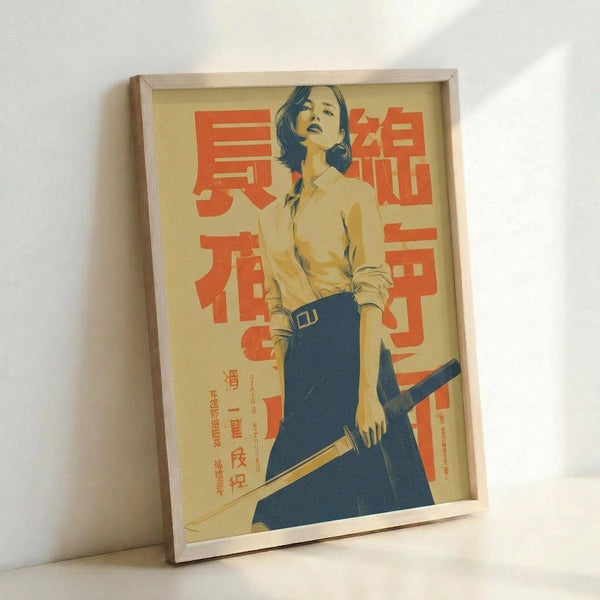 May include: Framed vintage-style poster featuring a woman in samurai attire holding a katana sword, rendered in yellow, blue and red color palette with Japanese text, displayed in light wood frame leaning against white wall corner