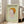 May include: Framed art print featuring a stylized child-like figure with orange hair emerging from rippling water against a soft green background, displayed in light wood frame leaning against white wall next to beige upholstered chair in bright, naturally-lit room with hardwood floors.
