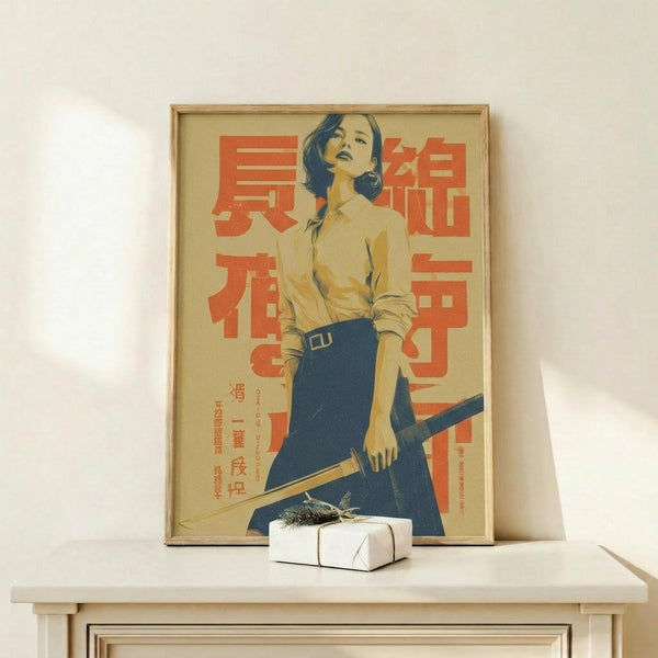 May include: Framed vintage-style poster featuring a woman in yellow blouse and blue skirt holding a katana sword, with red Japanese text on beige background. Wooden frame sits on white shelf next to small wrapped gift with dried sprig. Clean white wall backdrop creates minimalist display setting.