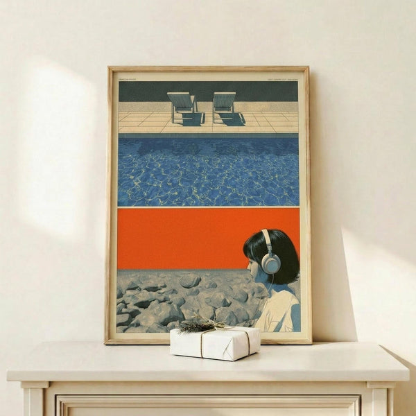 May include: Framed art print displayed on light wood console showing stylized illustration with horizontal color bands - green hedge with poolside chairs at top, blue swimming pool water in middle, bright orange section, and bottom panel featuring woman with headphones and dark hair against rocky landscape. Natural wood frame with white matting, small wrapped gift box nearby.