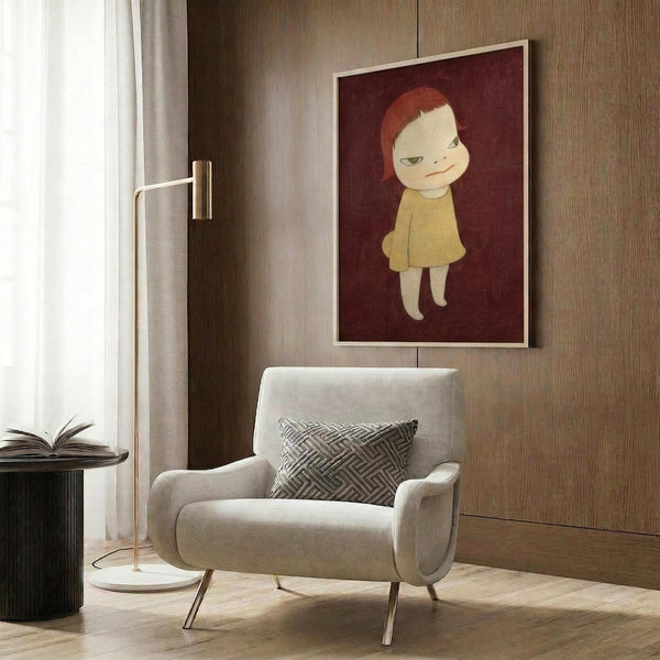 May include: Contemporary art print displayed in modern living room setting with beige armchair, geometric pillow, brass floor lamp, and dark wood paneling. Artwork shows stylized child figure with red-orange hair wearing yellow dress against deep burgundy background, housed in light wood frame.