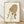 May include: Framed art print featuring a stylized cartoon girl with large blonde beehive hair and oversized eyes, wearing a mint green dress. The illustration has a minimalist style with soft colors on cream background, displayed in a light wood frame leaning against a white textured wall on wooden flooring with natural lighting creating gentle shadows.