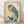 May include: Framed vintage Japanese woodblock print featuring an owl with large golden eyes perched on a branch with teal-blue leaves. The owl has detailed feather patterns in cream, brown, and blue tones against a beige background. Japanese text characters appear in the upper right corner with a red seal stamp on the left. The artwork is displayed in a light wooden frame, leaning against a white wall on light wood flooring with soft natural lighting.
