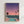 May include: Framed poster print displayed on white wall featuring retro-style cityscape illustration. Shows turquoise swimming pool on pink terrace overlooking illuminated city skyline at dusk. Three dark palm trees silhouetted against gradient sky transitioning from deep purple to coral pink. Small airplane visible in distance. Modern architectural elements include glass structure beside pool. Light wood frame surrounds artwork in minimalist room setting.