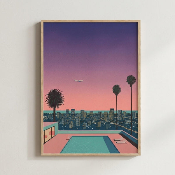 May include: Framed poster print displayed on white wall featuring retro-style cityscape illustration. Shows turquoise swimming pool on pink terrace overlooking illuminated city skyline at dusk. Three dark palm trees silhouetted against gradient sky transitioning from deep purple to coral pink. Small airplane visible in distance. Modern architectural elements include glass structure beside pool. Light wood frame surrounds artwork in minimalist room setting.