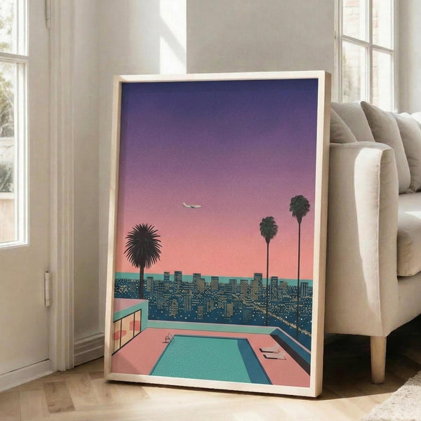May include: Framed poster print leaning against white wall next to beige sofa in bright room with large windows. Artwork shows retro-style illustration with gradient purple-to-pink sunset sky, three palm tree silhouettes, city skyline with lit buildings, and turquoise swimming pool in foreground. Print has light wood frame and vibrant 1980s aesthetic with coral, teal, and violet colors.