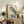 May include: Framed vintage Japanese woodblock print of an owl with blue wings and detailed feather patterns perched on flowering branch, displayed on rustic wooden sideboard alongside books, ceramic vases, and potted fern in neutral-toned living room setting.