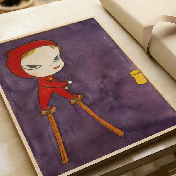 A cartoon-style illustration featuring a pale child character with blonde hair wearing a red hooded outfit and orange wooden skis, set against a purple background. The character has a simple, minimalist face with dark eyes and appears to be skiing, with a yellow rectangular shape visible in the upper right corner. The artwork is displayed as a print on white paper with additional papers visible in the background, showing the flat poster format with soft, muted colors and a whimsical, innocent ar