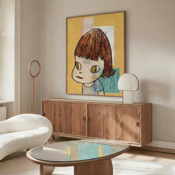 May include: Modern living room with warm wood sideboard displaying framed artwork featuring cartoon-style girl with brown bob haircut and large yellow-green eyes on bright yellow background with collaged paper elements. White curved chair and glass coffee table visible in foreground, copper floor lamp stands nearby.