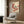 May include: Vintage Japanese bird artwork displayed on wood-paneled wall above beige upholstered chair with geometric pillow. Print shows small songbird perched on branch with clusters of red berries against cream background. Modern reading corner with brass floor lamp and dark side table.