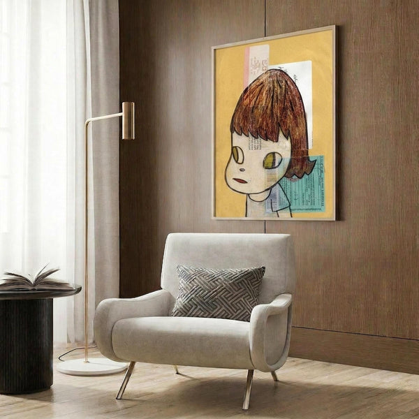May include: Contemporary art print featuring a stylized character with brown bob haircut and large yellow-green eyes on a warm yellow background with collaged text elements, displayed in thin gold frame on wood-paneled wall above cream upholstered armchair with geometric throw pillow, brass floor lamp and side table with open book nearby