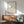 May include: Minimalist line drawing of woman submerged in wavy water, shown from behind with flowing hair. Black ink illustration on cream background in thin wooden frame, displayed above walnut sideboard with ceramic table lamp. Mid-century modern living room with sage green upholstered chair and round coffee table. Bright natural light creates geometric shadows on white wall.